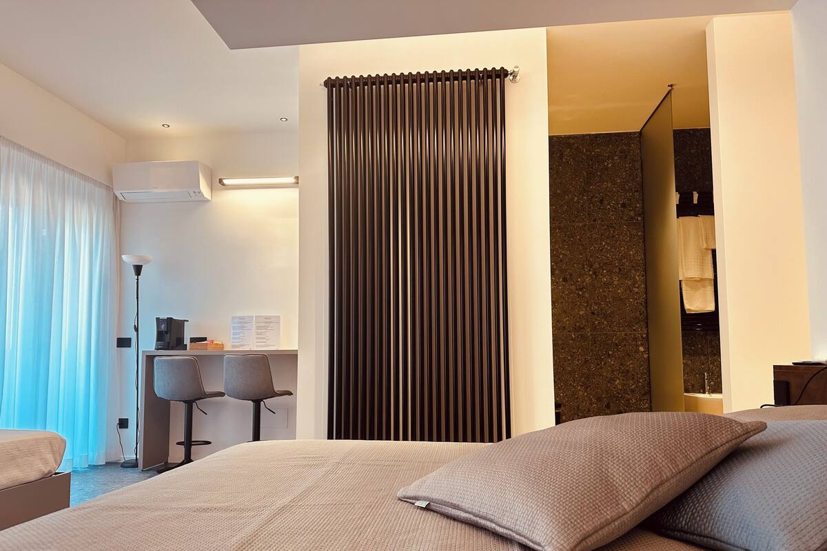 Ein modernes Hotelzimmer mit einem großen Bett, einem Schreibtisch und einer Duschkabine.