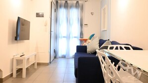 Una habitación de hotel con televisión, una mesita, un sofá y una ventana con cortinas.