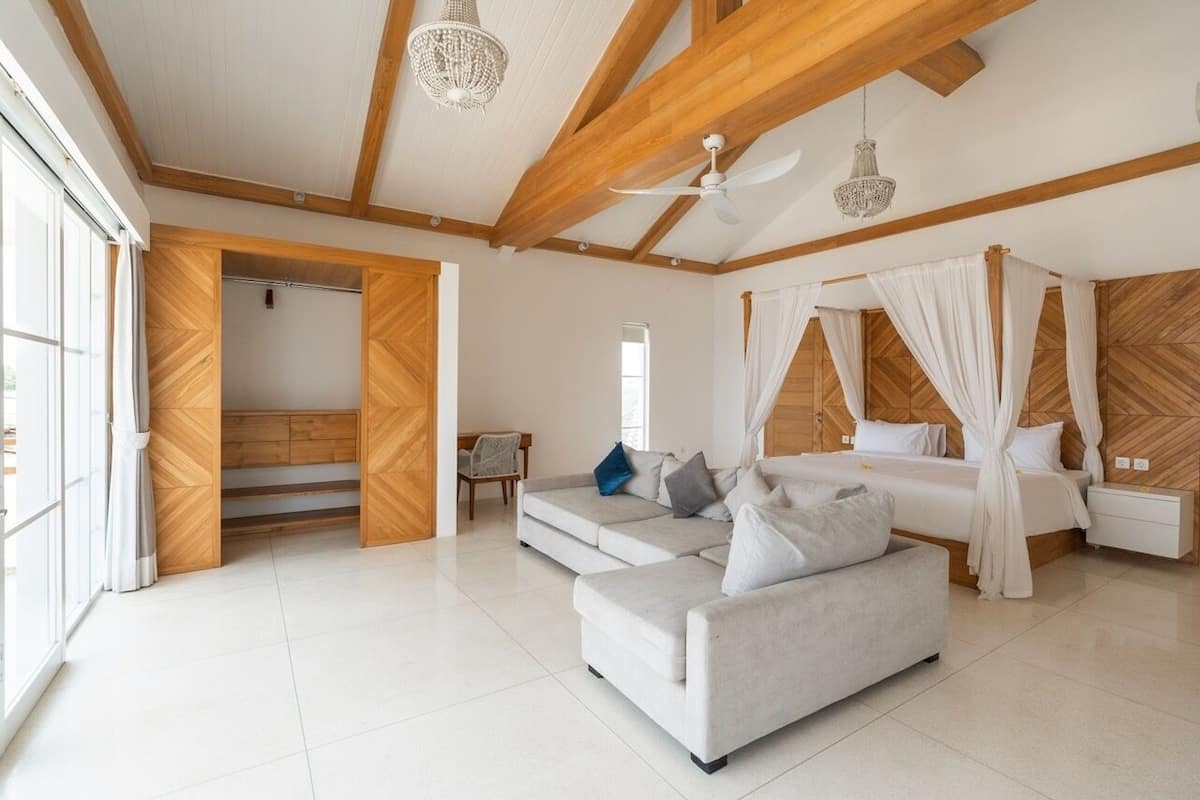 A spacious bedroom with a large bed, a sofa, and a ceiling fan.