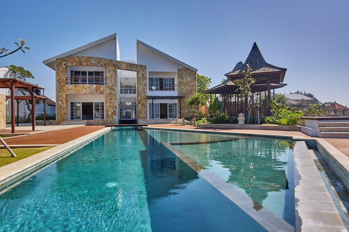 A modern house with a swimming pool, stone facade, and a gazebo.