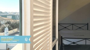 Un balcon avec un lit, une vue sur des immeubles et une enseigne indiquant un restaurant.