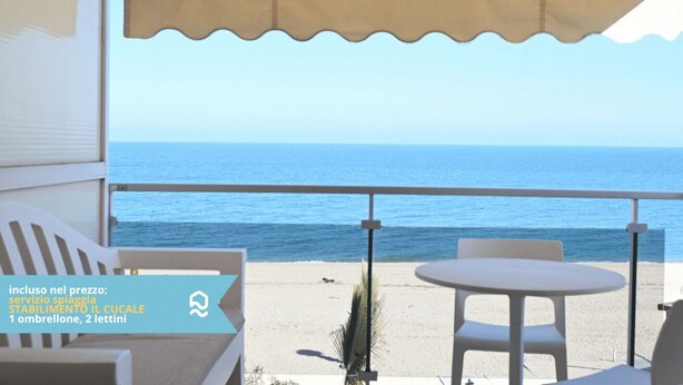 Un balcon avec vue sur la mer, une table et deux chaises.