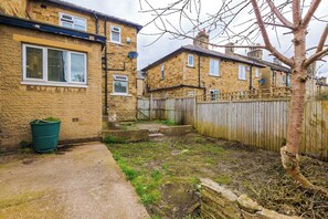 A residential area with two stone houses, a wooden fence, and a tree.