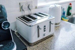 A kitchen with a white toaster, a coffee maker, and a sink.