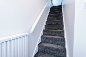 A staircase with dark carpeted steps and white walls.