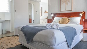A neatly made bed with a headboard, a bedside table with a lamp, and a framed picture on the wall. - Pacific Sun Bargara ~ by the beach (Bargara)
