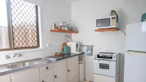 A compact kitchen with a sink, a microwave, a toaster, and a refrigerator. - Pacific Sun Bargara ~ by the beach (Bargara)