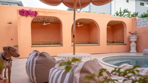 A poolside area with a covered seating area, a pool, and a dog. - Pacific Sun Bargara ~ by the beach (Bargara)
