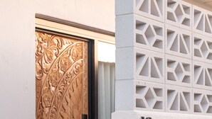 A door with intricate carvings, a glass panel, and a number '10' on a white wall. - Pacific Sun Bargara ~ by the beach (Bargara)