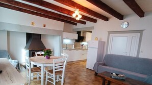 A cozy living area with a fireplace, a dining table with chairs, and a sofa. - Gîtes de France® - Gîte de Lacroux (LINAC)