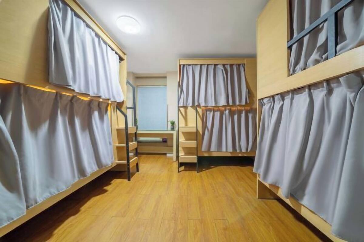 Un dormitorio con literas, suelo de madera y un pequeño escritorio con silla.