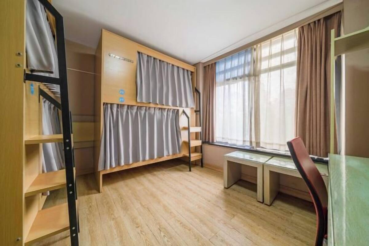 Una habitación tipo dormitorio con literas, un escritorio y una silla.