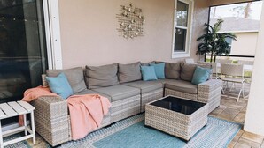 A cozy outdoor seating area with a wicker sofa, a small table, and a coffee table.