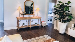A living room with a wooden console table, two lamps, a large mirror, and a potted plant.