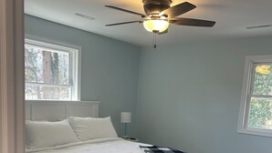 Une chambre à coucher avec un lit, un ventilateur de plafond et une fenêtre.