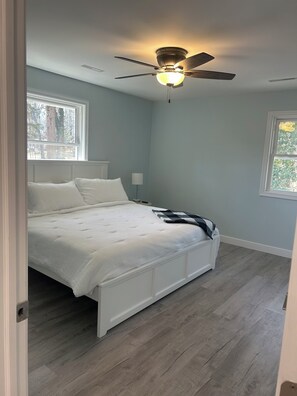 Un dormitorio con cama, ventilador de techo y ventana.