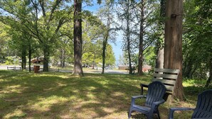 Un parc avec un banc et des fauteuils Adirondack, entouré d’arbres et sous un ciel dégagé.