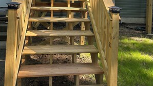 A wooden staircase leading to a deck with railings.