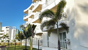A modern multi-story building with balconies, surrounded by well-maintained grass and a paved walkway.