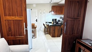 A spacious living area with a sofa, a kitchen with wooden cabinets, and a dining area with chairs.