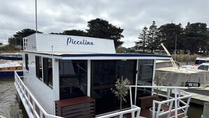 A stationary houseboat named Piccolina docked at a marina.