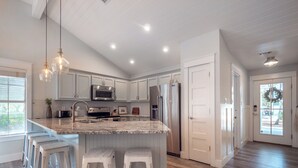 A spacious kitchen with a large island, stainless steel appliances, and white cabinetry. - Walk to Beach & Dinner! Charming 1-Level Cottage ♥ Pets + Fenced Yard w/ Grille (Santa Rosa Beach)