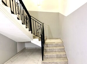 Stairs lead to an upper floor with a plain white wall and a light-colored tile floor.