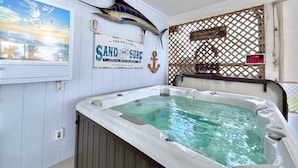 A room with a large hot tub, a sailfish mounted on the wall, and a sign that reads "Sand and Surf".