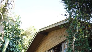 A wooden house with a balcony, surrounded by dense foliage. - Solitude Cabin - Sailor (Pântano do Sul)