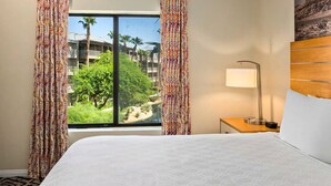 A hotel room with a bed, a nightstand, a lamp, and a window with curtains. - 2-bedroom resort in fabulous Indio with fitness room, AC. Relax and enjoy (Indio)