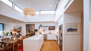 A modern kitchen with a central island, white cabinetry, and a red carpet. - Nautilus - Sleeps 8 - Lake Views (Wanaka)