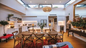 A spacious dining area with a high ceiling, modern kitchen, and large windows. - Nautilus - Sleeps 8 - Lake Views (Wanaka)