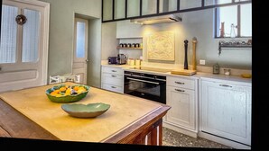 Una cocina con armarios blancos, microondas, cafetera y frutero sobre la encimera.