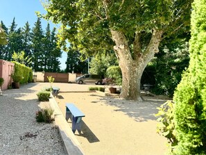 A gravel parking area with a bench, a tree, and a car parked in the background. - Villa SQUIRREL, located between St. Rémy and Noves. What a beautiful pool! (Verquiéres)