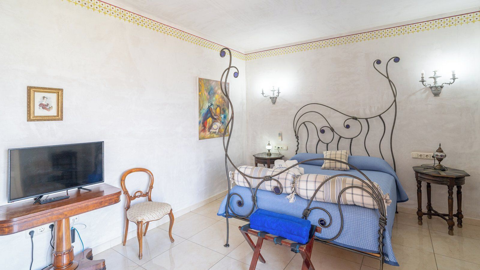 Une chambre à coucher avec un lit, une télévision, une chaise, un tableau et une lampe.