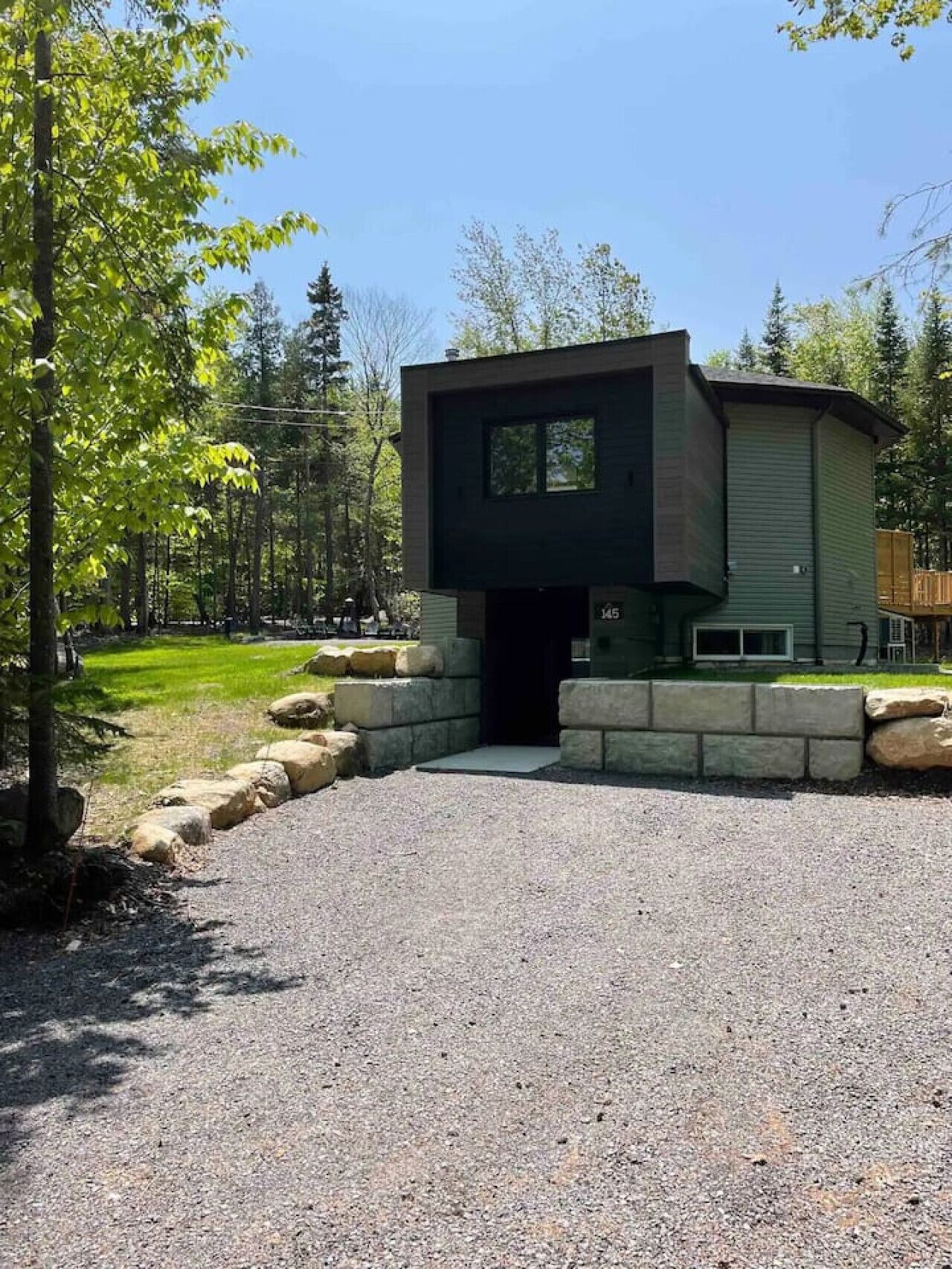 A modern building with a flat roof, a large window, and a stone foundation.
