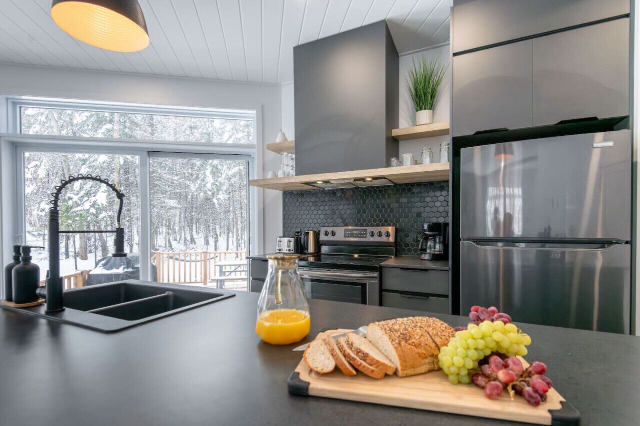 A modern kitchen with a large island, stainless steel appliances, and a view of a snowy landscape.