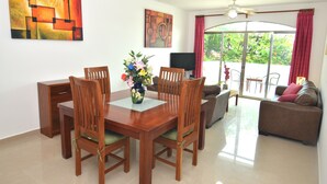 A dining area with a wooden table and chairs, a vase of flowers, and a ceiling fan.