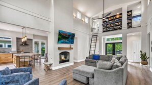 Un salón amplio con chimenea, un televisor grande y un techo alto con tragaluces.