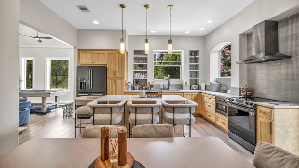 Una cocina moderna con una isla central, armarios de madera y una campana extractora de acero inoxidable.