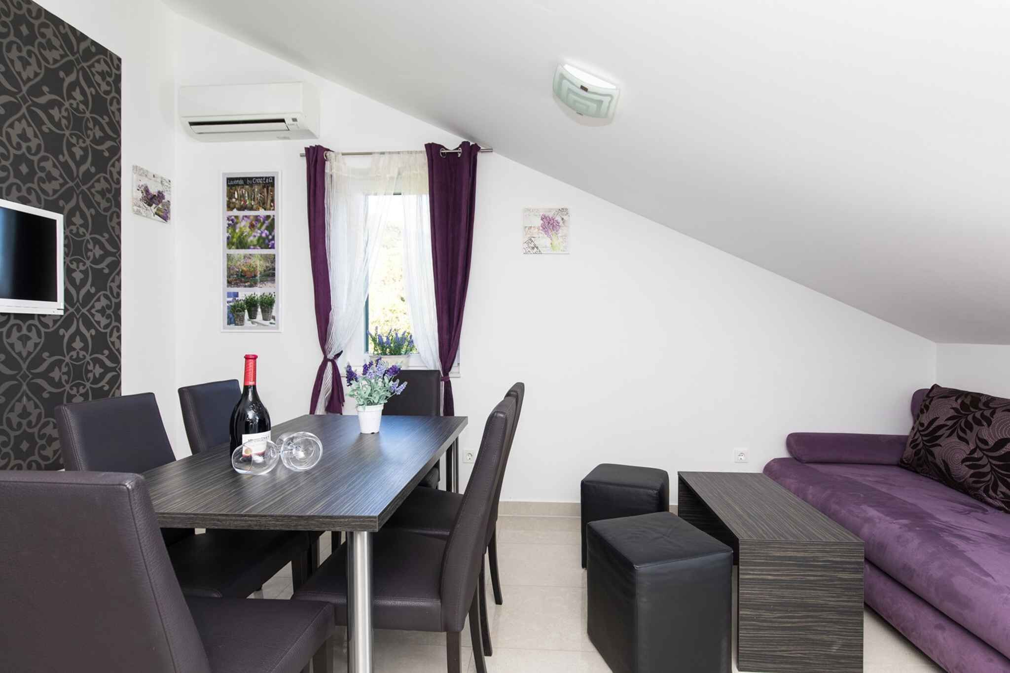 A dining area with a table, chairs, a wine bottle, and a vase of flowers.