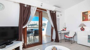 Ein modernes Zimmer mit Fernseher, Essbereich und Blick auf eine gebirgige Landschaft.