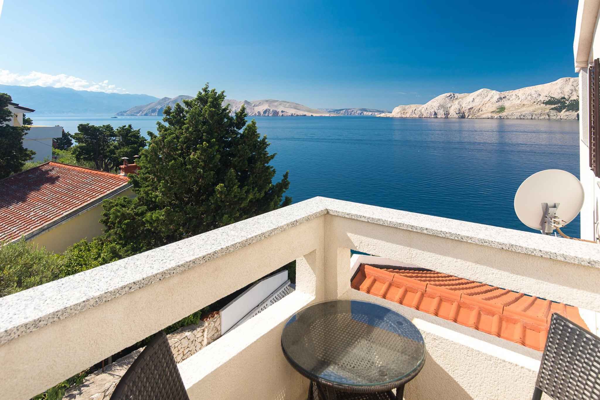 A balcony with a view of the sea, a satellite dish, and a table.