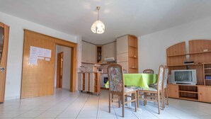 Un vaste espace de vie comprenant une table à manger, des chaises, un téléviseur et des meubles de rangement en bois.