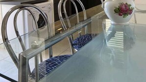 Una cucina moderna con un tavolo da pranzo in vetro, sedie in acciaio inossidabile e un vaso bianco con decorazioni floreali.