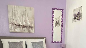 Una camera da letto con un letto, cuscini, un comodino, una lampada e opere d'arte alle pareti.