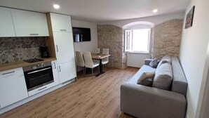 A compact living space with a kitchenette, dining area, and seating area. - Holiday apartment near the sea (Baška)