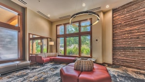 A modern lobby with a large seating area, large windows, and a unique wooden wall.