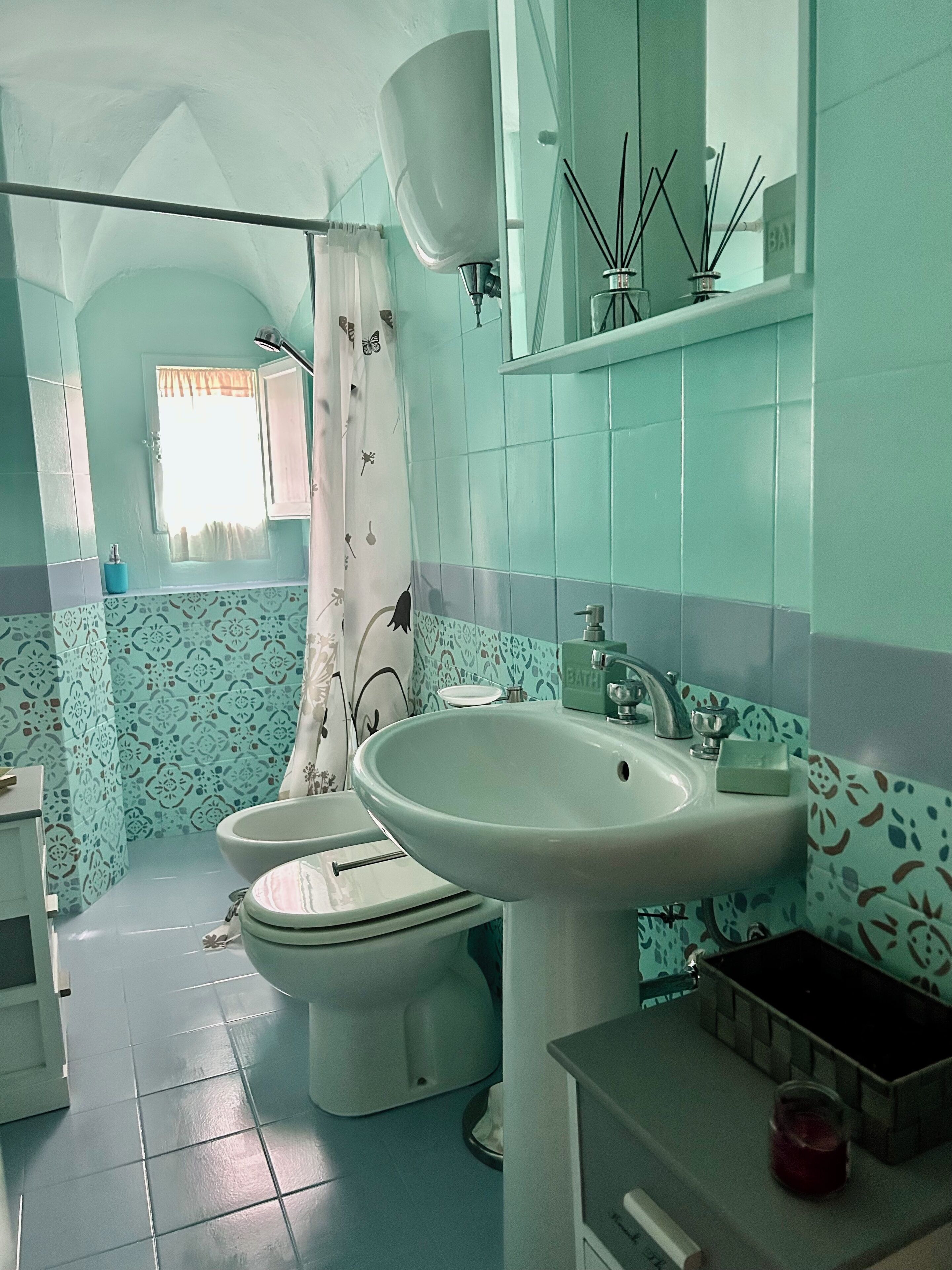 A bathroom with a toilet, bidet, sink, and a mirror above the sink.