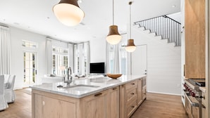 Una cocina moderna con una isla grande, armarios de madera e iluminación colgante.